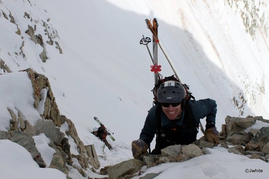 Anton smiling as he balances on loose rock, with me crouching below.
