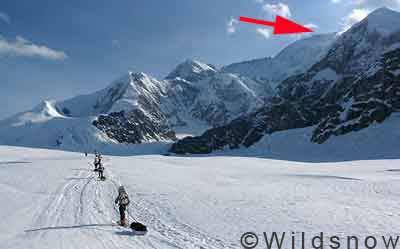 denali-first-slog Heading up Kahiltna Glacier to Camp One, summit regions of Denali taunt you to the right, indicated by red arrow. The climbing route swings around to the left.