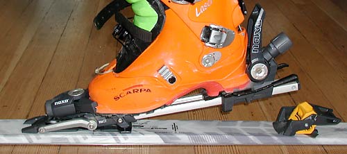 Naxo binding in touring mode, showing double toe pivot at first stage of stride. The double pivot allows a somewhat natural stride, but more, it allows the use of a full size alpine-like toe. The binding weighs about the same as a Diamir Freeride, and is sold with brakes. Heel lifter is designed so that the binding can not accidently switch to touring mode while alpine skiing -- a concern of some hard cores.