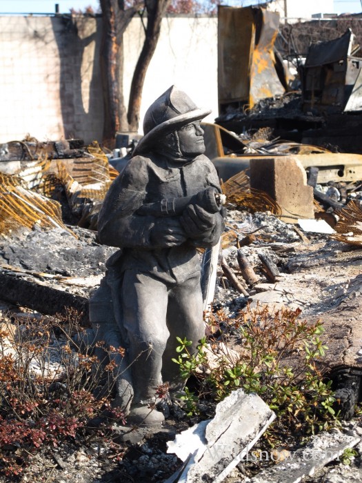 A lone firefighter statue in front of a charred house in the Rockaways. 