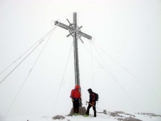 Franz bergheils each skier at the ice encrusted summit cross.