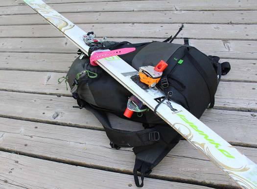 Diagonal ski carry using center buckle strap. Diagonal ski carry using center buckle strap.