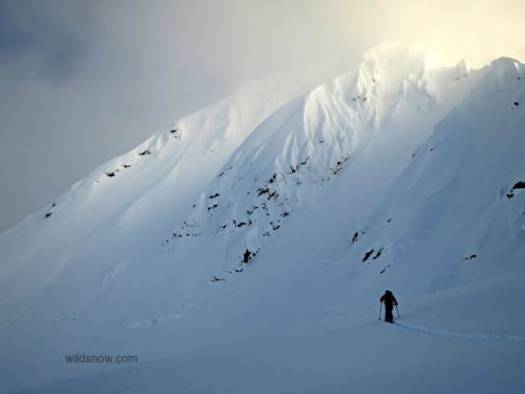 Zach skinning with the massive NE face of Tomahawk peeking out of the clouds. Zach skinning with the massive NE face of Tomahawk peeking out of the clouds.