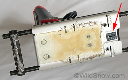 Underside of heel unit, arrow indicates scale for lateral release setting. For boot length adjustment this assembly slides on the binding rails when you move the tabs visible above and below the scale. Underside of heel unit, arrow indicates scale for lateral release setting. For boot length adjustment this assembly slides on the binding rails when you move the tabs visible above and below the scale.