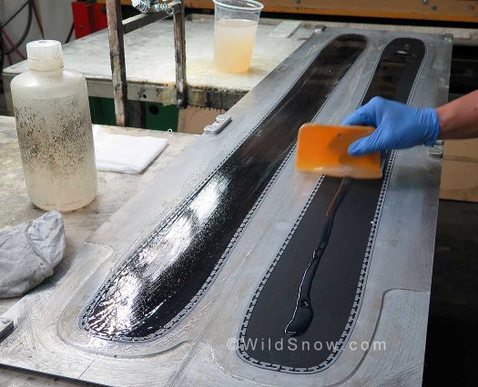 The layup in lower part of mold, with the edges and other components inserted, resin being troweled in. The layup in lower part of mold, with the edges and other components inserted, resin being troweled in.