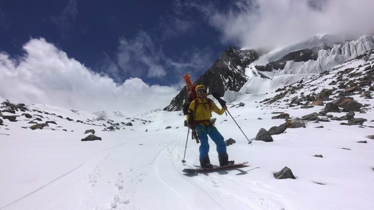 Poles in Hand proving useful while crossing flat variable terrain with an enormous pack and alternative snowboard methods. . Zhongshan Feng, China. Photo: Liu Jin Fu
