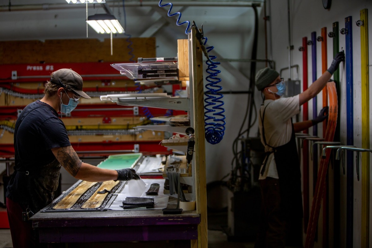 The layup room is where the pieces of the puzzle all come together before getting glued, pressed, and stamped. You can see the unique ski press in the background of this shot. In the foreground there is a layup in progress.