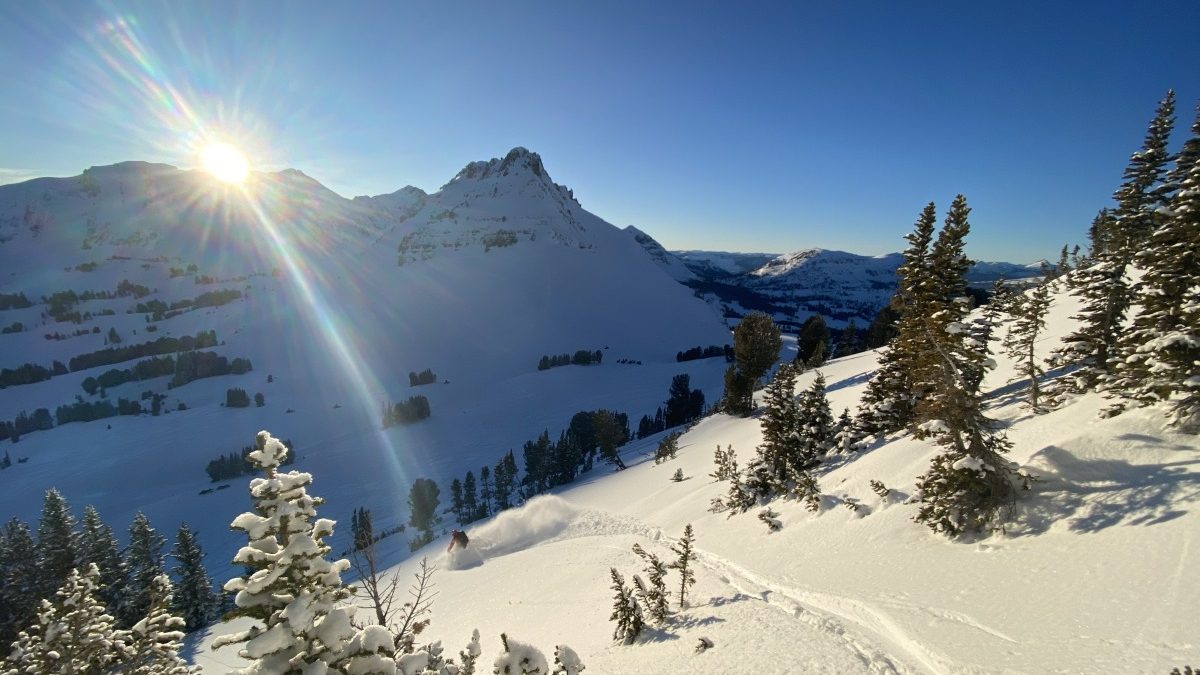 On day five, we decided to get a little “alpine-y”. It was fun to enjoy the new snow in the sun. We were still keeping it pretty mellow overall but snowmobiles around us were not holding back and making some good snowpack tests. In this photo Louis is descending down towards Crown Butte, seen in the background to the right of the sun. The next day a snowmobiler actually triggered a slide (no one was hurt) on Crown Butte, even after the mountain had been what felt like bombarded with sled traffic the day before.