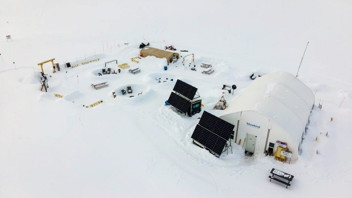 Base area from above. All skiers have to pass through the wooden archway to the left where they pass through a beacon checker, get their passes scanned, and show their shovels and probes to a staff person stationed there.
